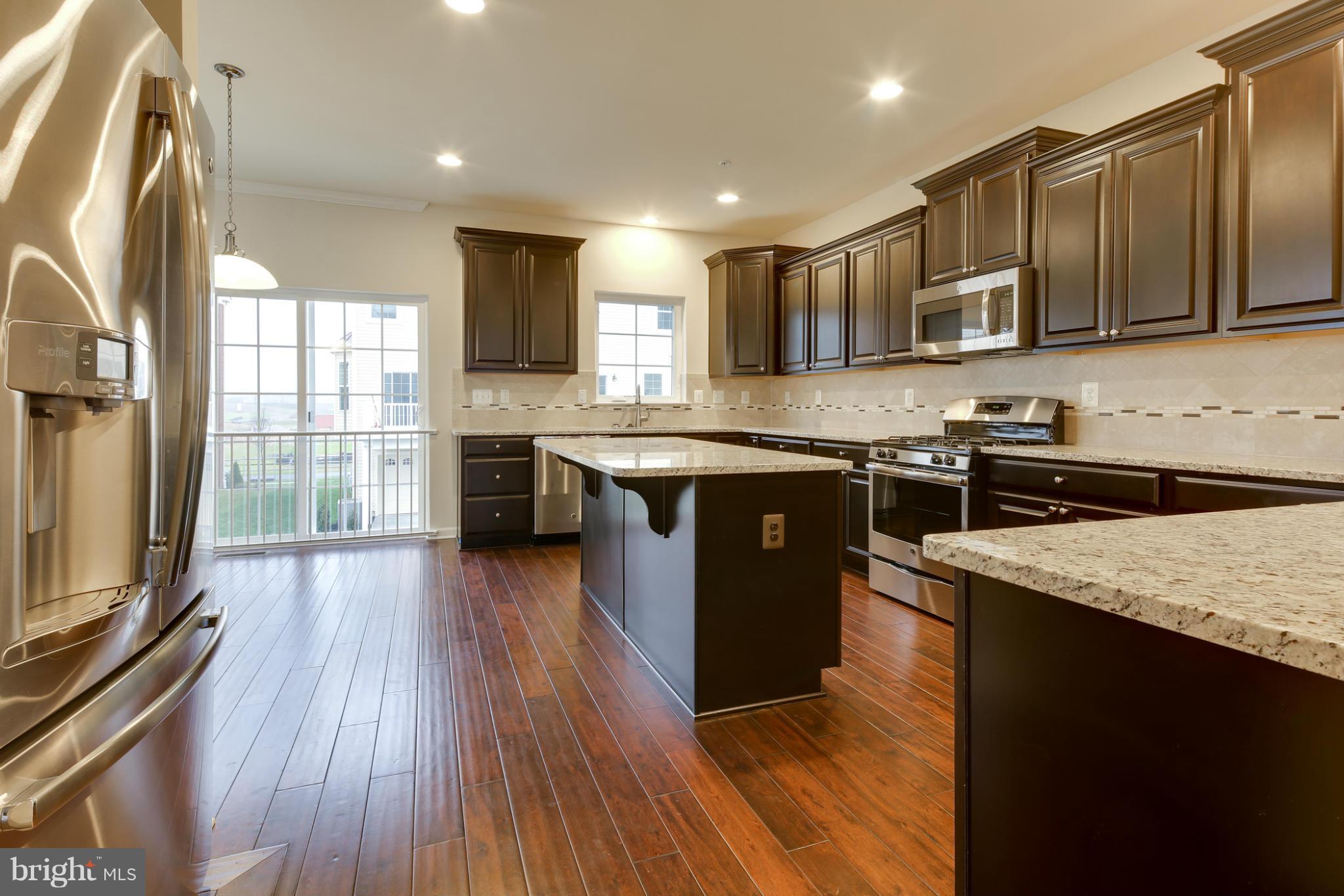 7240 Brinley Way Hanover, MD 21076 - Photo 6 of 22 a kitchen with stainless steel appliances granite countertop hardwood floor sink stove and wooden cabinets