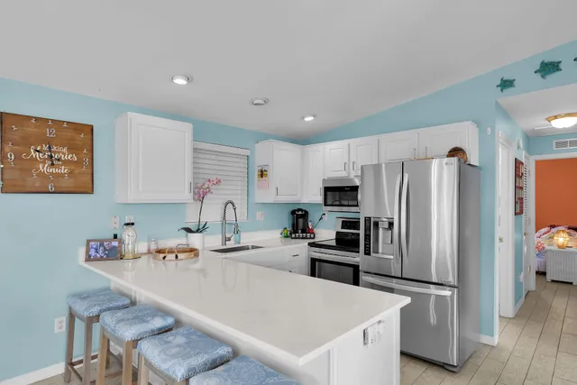 a kitchen with granite countertop a refrigerator a sink and white cabinets