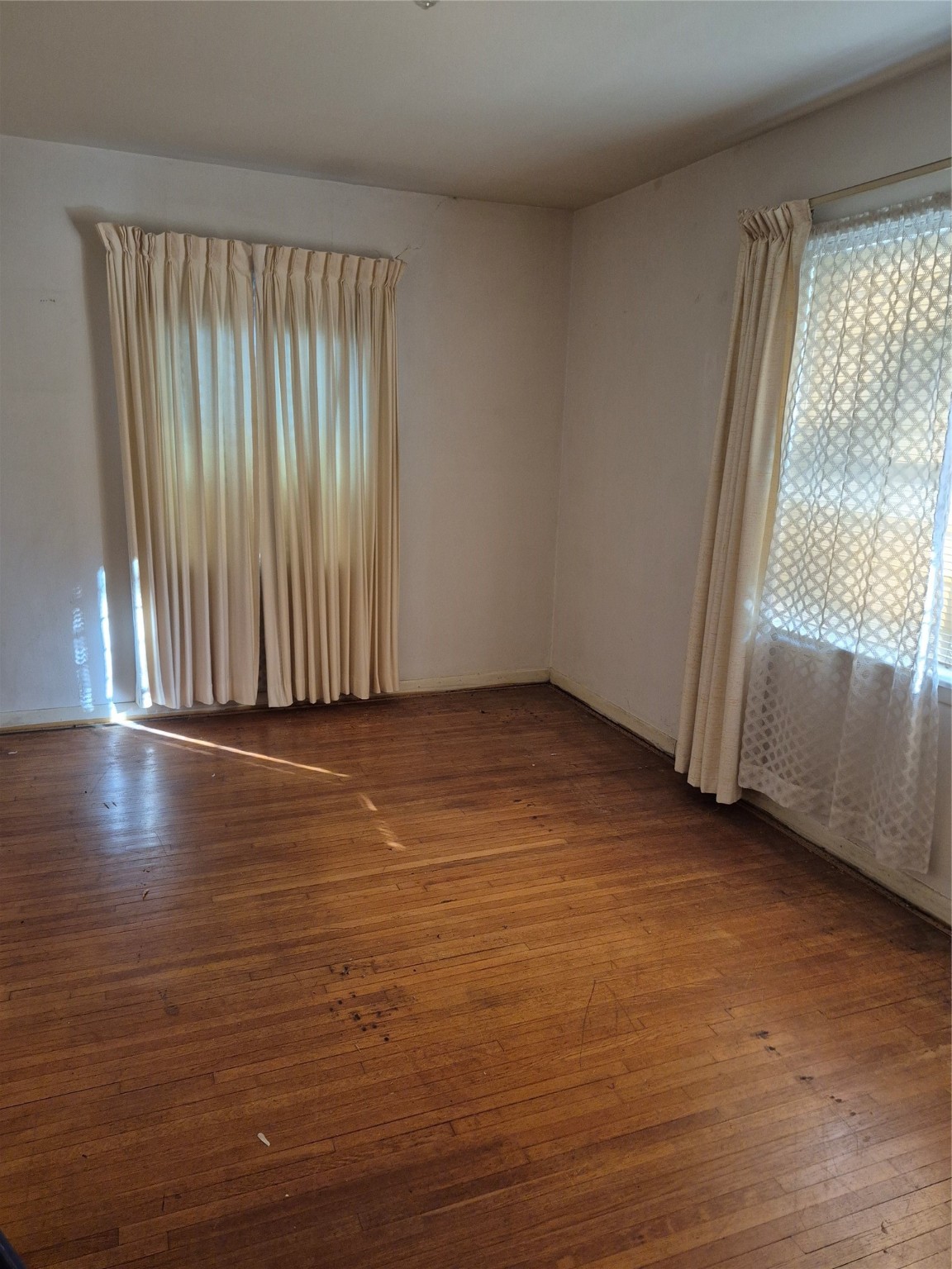 8046 Turquoise Lane Houston, TX 77055 - Photo 3 of 8 an empty room with wooden floor and windows with curtains