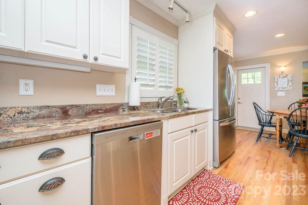 154 Rugby Drive Hendersonville, NC 28791 - Photo 17 of 48 a kitchen with granite countertop sink window and white cabinets