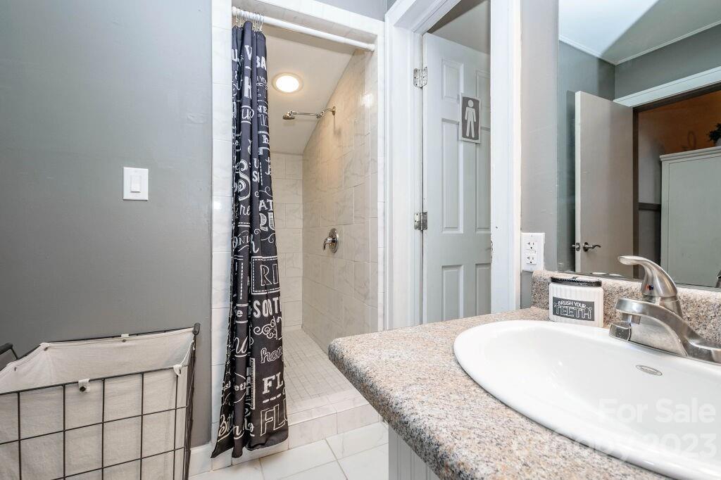154 Rugby Drive Hendersonville, NC 28791 - Photo 36 of 48 a bathroom with a granite countertop sink a mirror and shower
