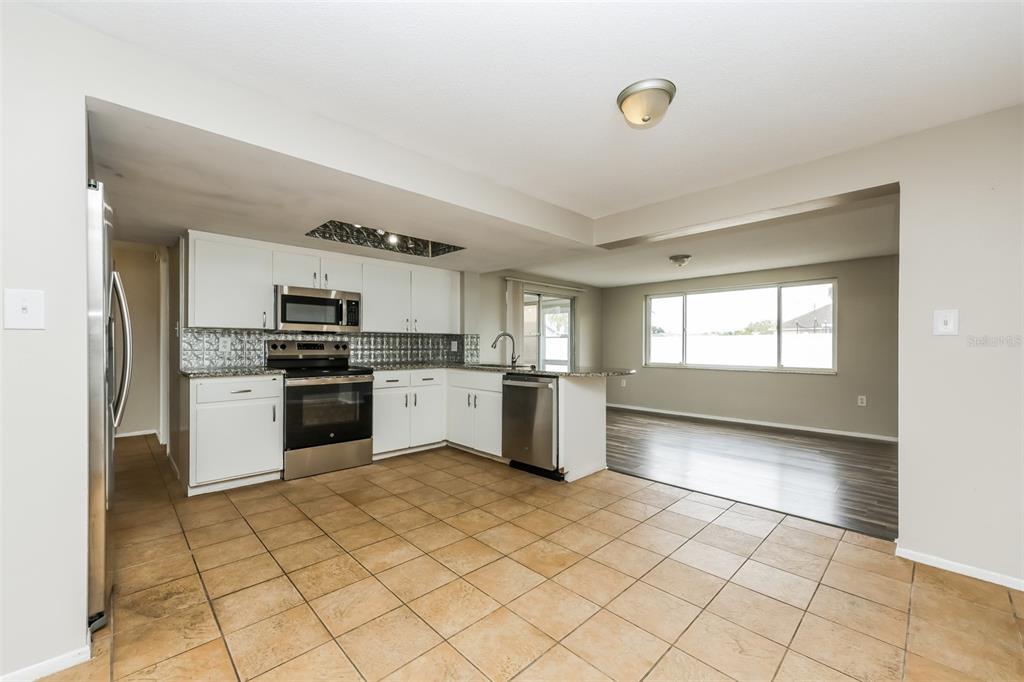 9436 Legend Lane Port Richey, FL 34668 - Photo 7 of 21 a kitchen with granite countertop a refrigerator and white cabinets