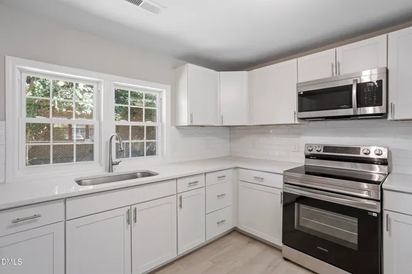a kitchen with cabinets stainless steel appliances and window
