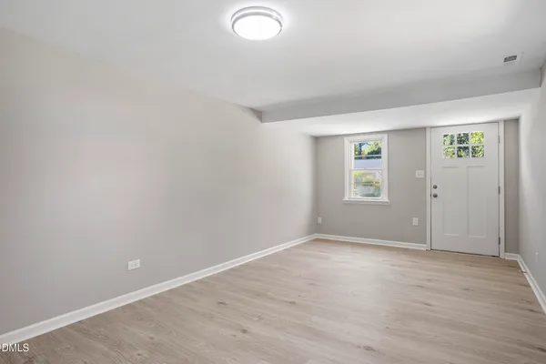 an empty room with wooden floor and windows