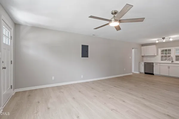 an empty room with wooden floor ceiling fan and windows