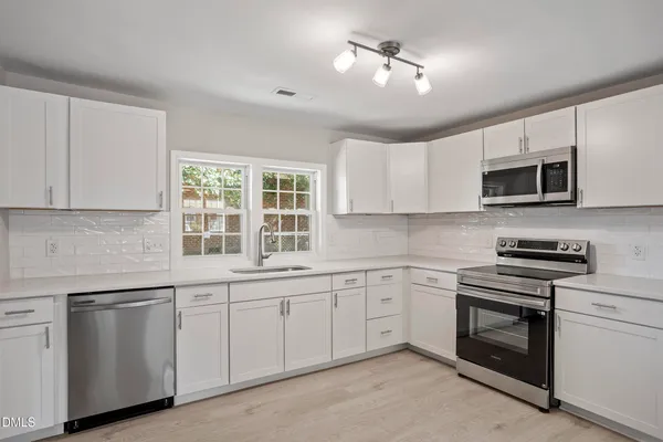 a kitchen with white cabinets stainless steel appliances and a window