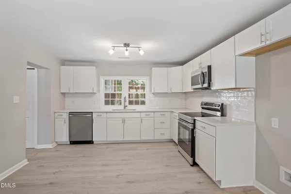 a kitchen with cabinets appliances a sink and a window