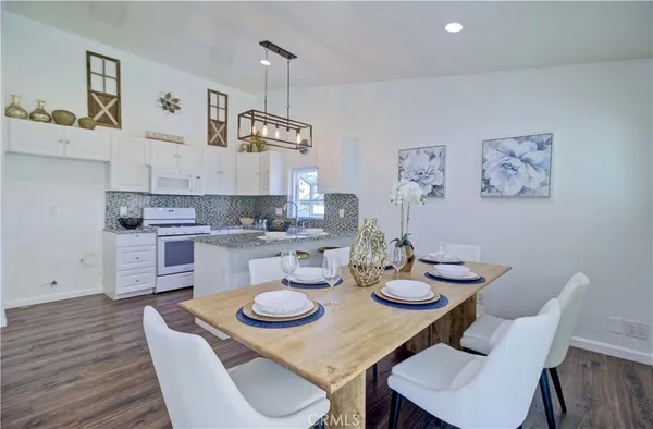 a kitchen with stainless steel appliances kitchen island granite countertop a table chairs and a stove
