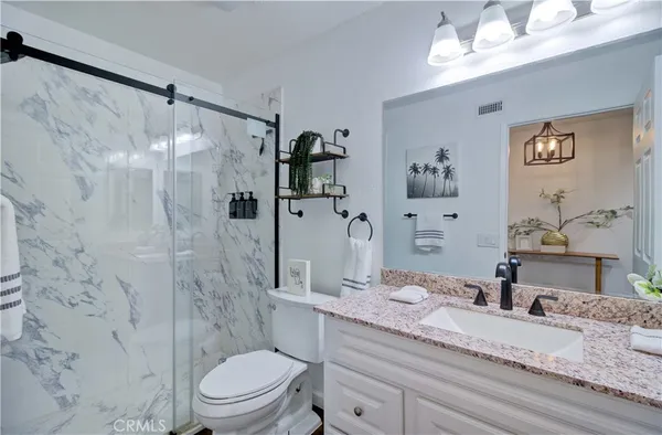 a bathroom with a granite countertop sink toilet a mirror a vanity and shower