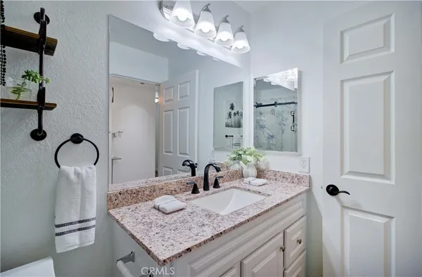 a bathroom with a granite countertop sink a mirror and shower