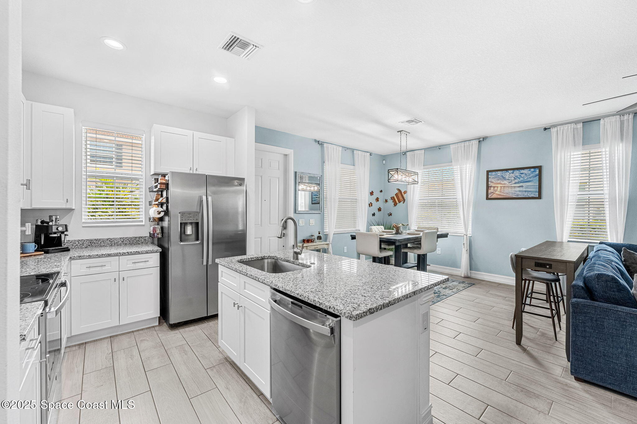 1810 Noel Place, Unit 107 Melbourne, FL 32935 - Photo 22 of 59 a kitchen with stainless steel appliances granite countertop a kitchen island a stove a refrigerator a sink a dining table and chairs