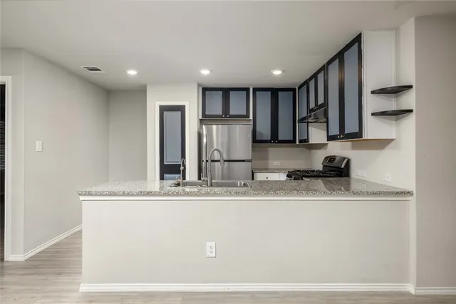 a kitchen with granite countertop kitchen island stainless steel appliances a refrigerator stove top oven and sink