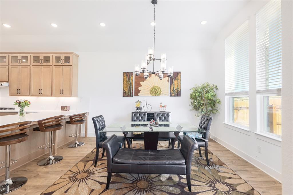 916 Willie Rnch Way Leander, TX 78641 - Photo 12 of 38 Dining area featuring a modern chandelier, hardwood floors, and tall windows providing natural light