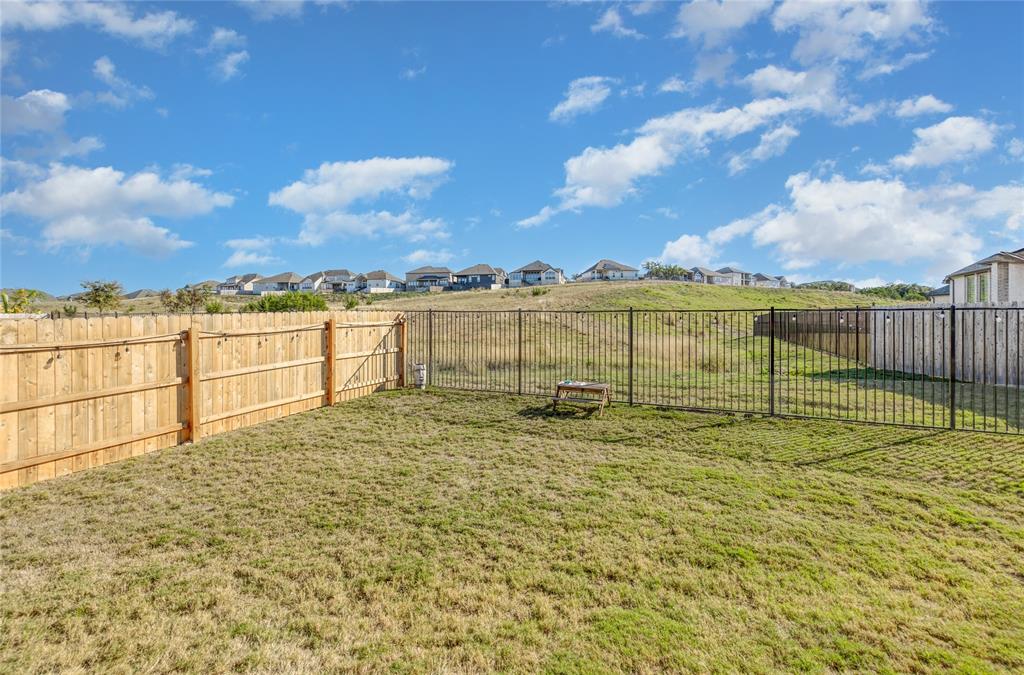 916 Willie Rnch Way Leander, TX 78641 - Photo 35 of 38 The property features a spacious yard with a lawn, a wooden privacy fence, and a black metal fence