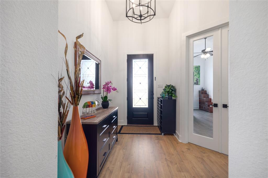 916 Willie Rnch Way Leander, TX 78641 - Photo 4 of 38 Entryway featuring light wood-style flooring, a dark-colored door with decorative glass inserts, and a stylish overhead light fixture