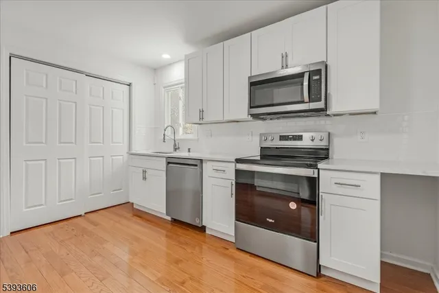 a kitchen with stainless steel appliances granite countertop a stove a microwave and white cabinets
