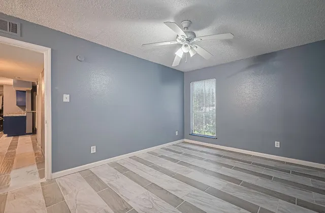 an empty room with windows and ceiling fan