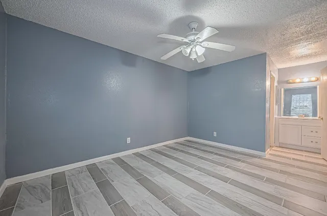 a view of an empty room with wooden floor and a chandelier fan