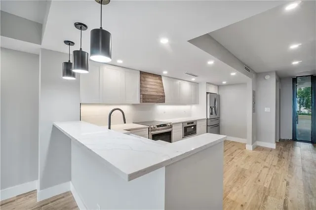 a kitchen with stainless steel appliances a sink a refrigerator and wooden floor