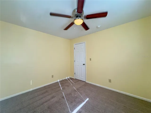 an empty room with ceiling fan and window