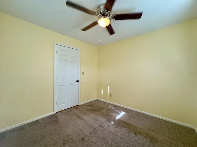 an empty room with a ceiling fan and carpet