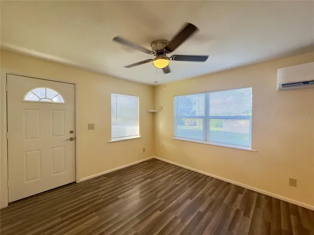 a view of an empty room with wooden floor and a window