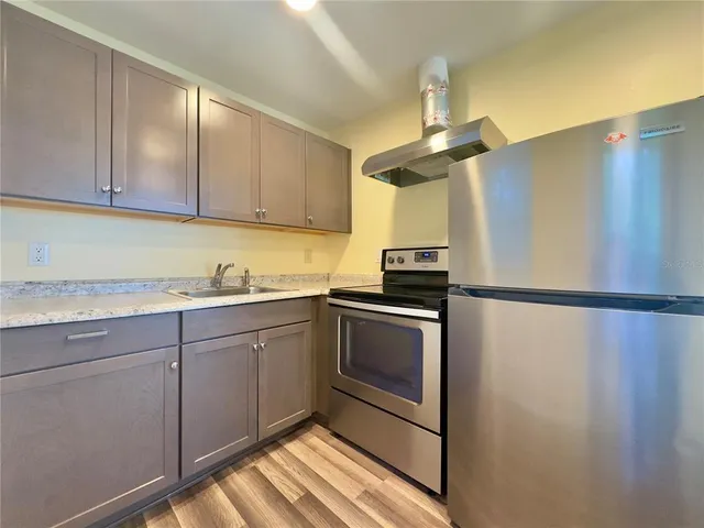 a kitchen with stainless steel appliances granite countertop a refrigerator a sink and white cabinets