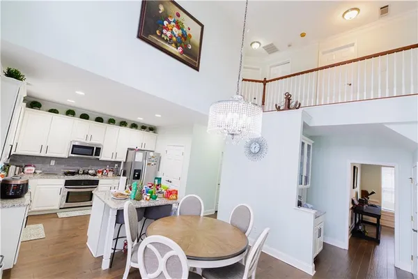 a kitchen with stainless steel appliances kitchen island granite countertop a table chairs in it and wooden floors