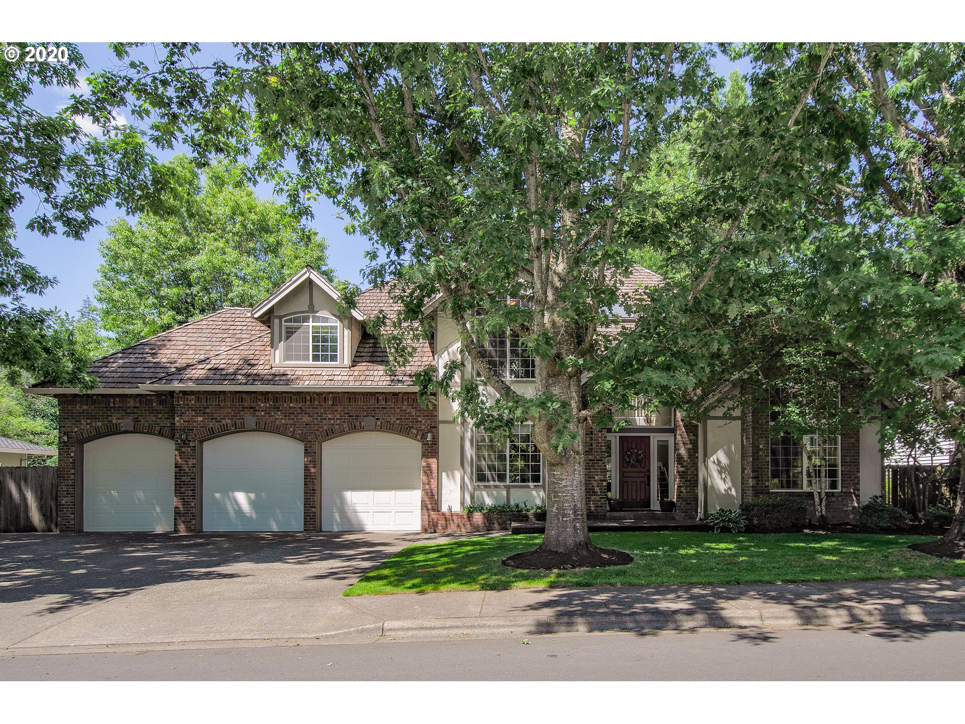 a front view of a house with a garden and tree