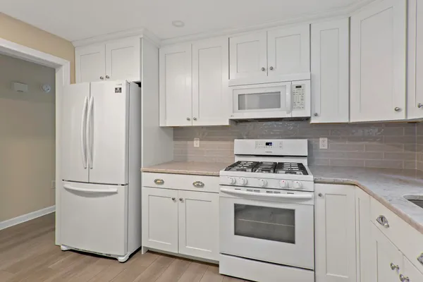 a kitchen with white cabinets and white appliances