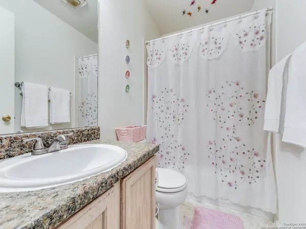 a bathroom with a granite countertop sink a toilet and a shower curtain