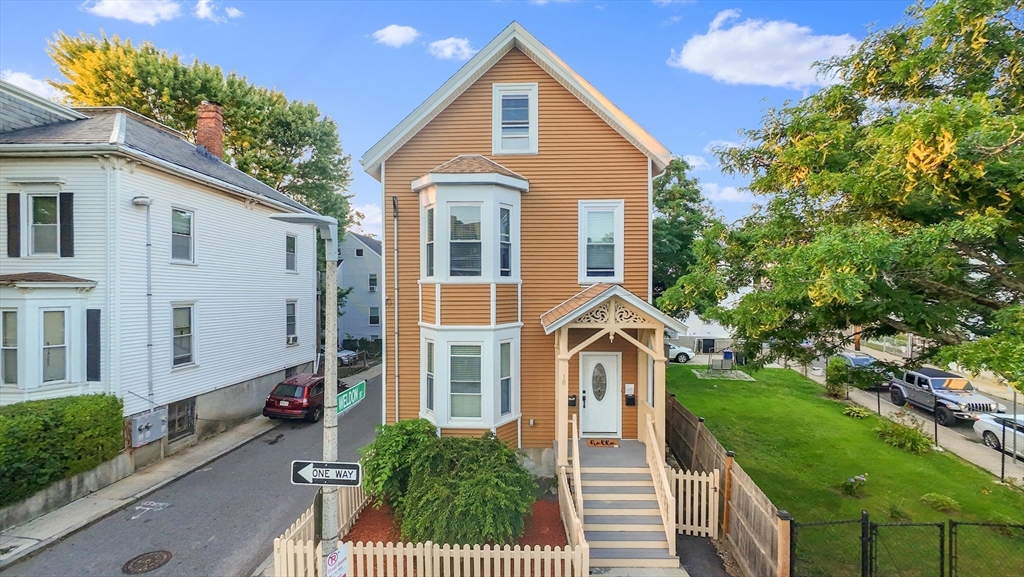 a view of a brick house with a yard plants and large tree