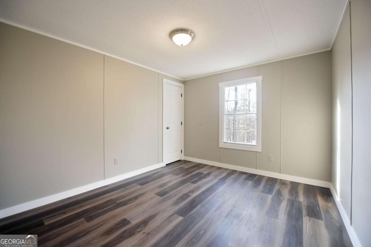 273 Rose Ray Road Ellijay, GA 30540 - Photo 20 of 32 a view of an empty room with wooden floor and a window