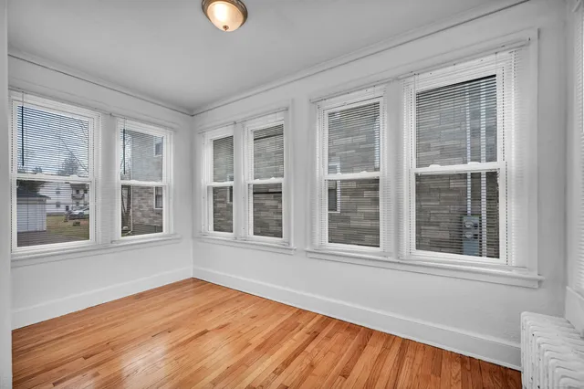 a view of an empty room with wooden floor and windows