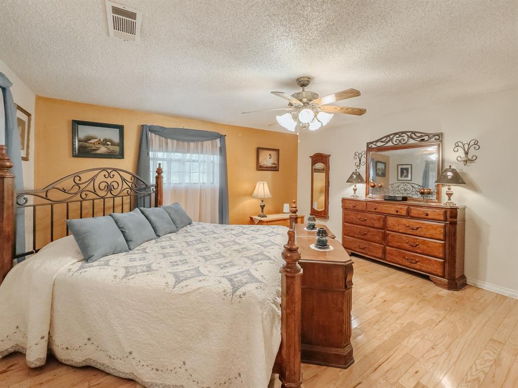 205 Peach Tree Road Mabank, TX 75156 - Photo 19 of 40 a bedroom with a bed and wooden floor