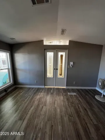 a view of an empty room with wooden floor and a window