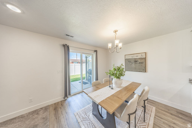 4991 South 475 West Washington Terrace, UT 84405 - Photo 12 of 31 Dining area featuring LVP flooring, a contemporary chandelier, and a sliding glass door providing access to an outdoor patio