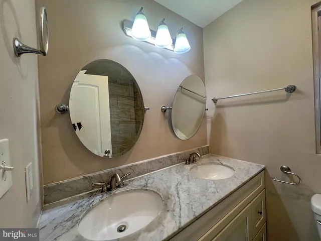 a bathroom with a granite countertop double vanity and a mirror