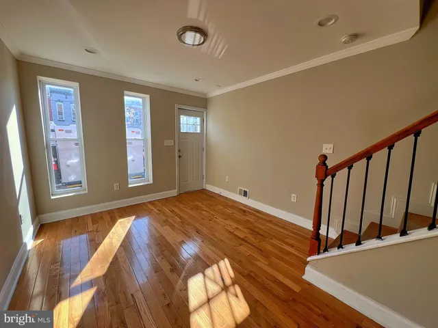 a view of an empty room with window and wooden floor