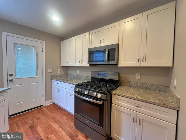 a kitchen with granite countertop a stove a microwave cabinets and a sink