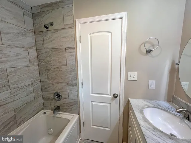 a bathroom with a granite countertop tub sink and mirror