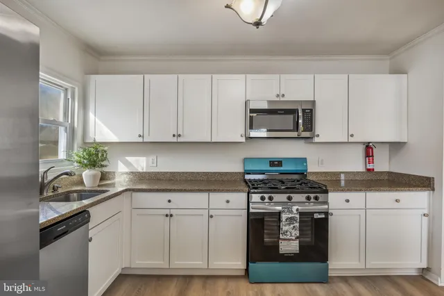 a kitchen with cabinets stainless steel appliances a sink and wooden floor