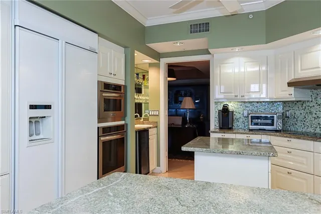 a kitchen with stainless steel appliances kitchen island a refrigerator sink and cabinets