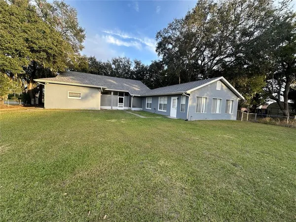 a view of a house with a yard and large trees