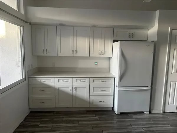 a kitchen with granite countertop a refrigerator and a stove top oven
