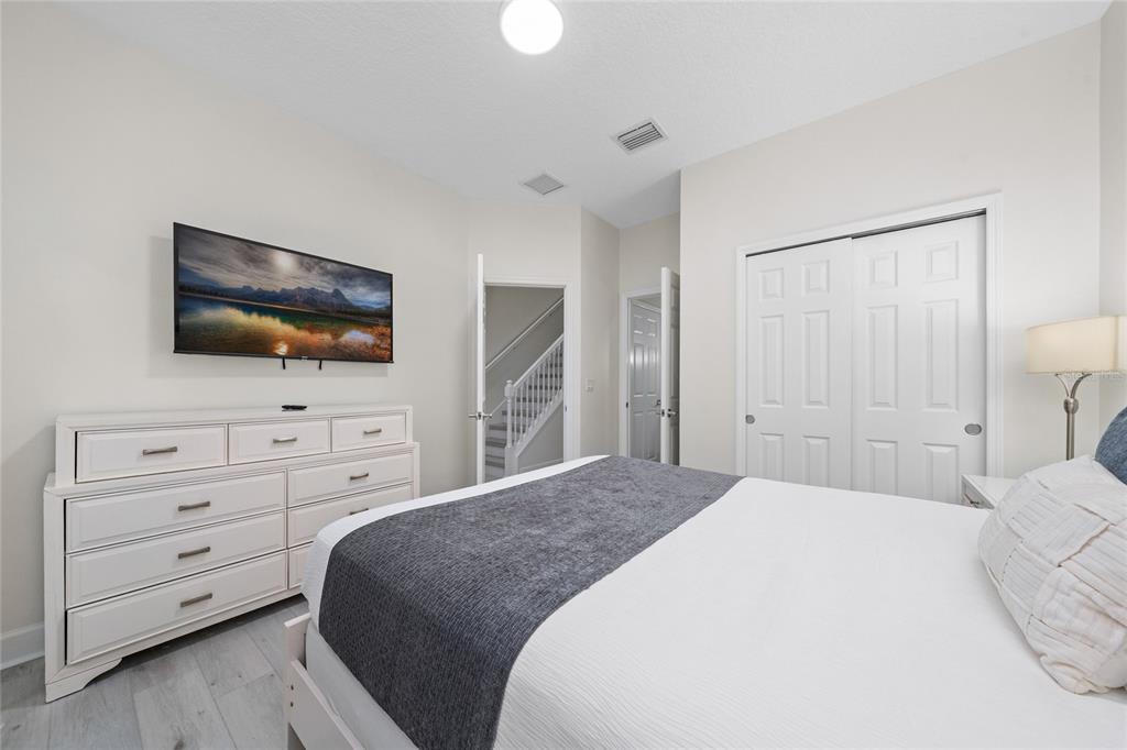 17417 Placidity Avenue Clermont, FL 34714 - Photo 17 of 25 a bedroom with a bed a flat screen tv and a chandelier