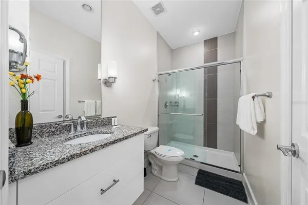 a bathroom with a granite countertop sink a toilet and shower