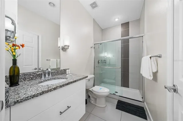 a bathroom with a granite countertop sink a toilet and shower