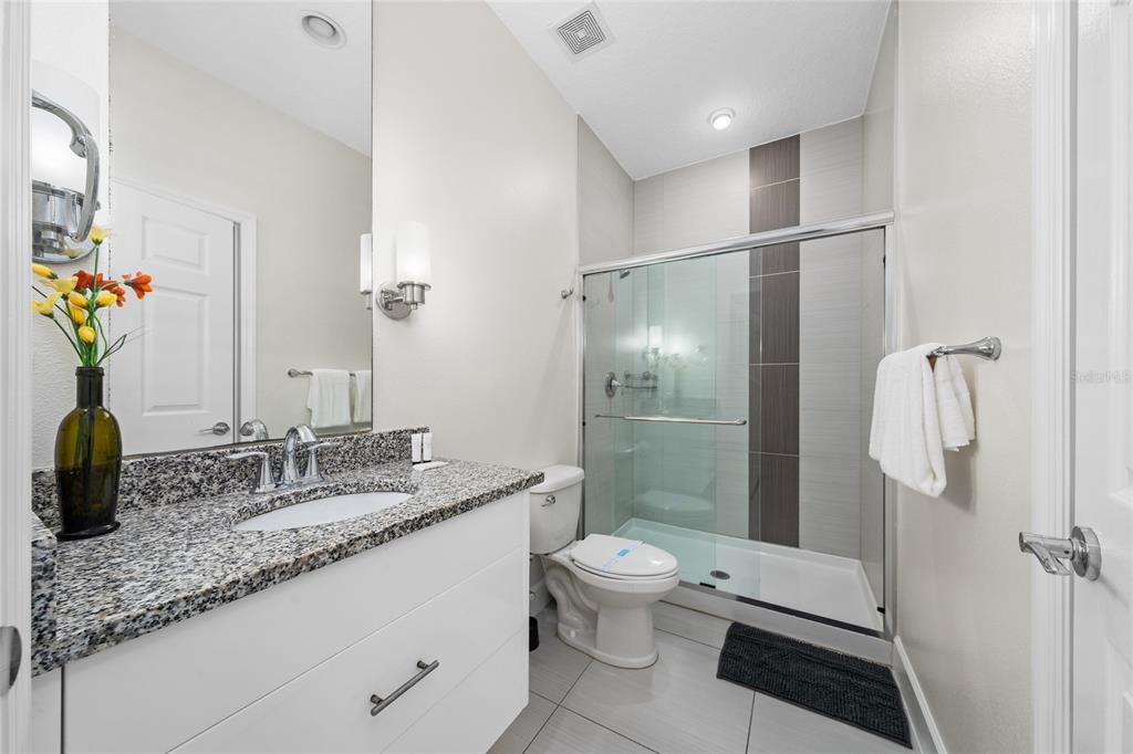 17417 Placidity Avenue Clermont, FL 34714 - Photo 10 of 25 a bathroom with a granite countertop sink a toilet and shower