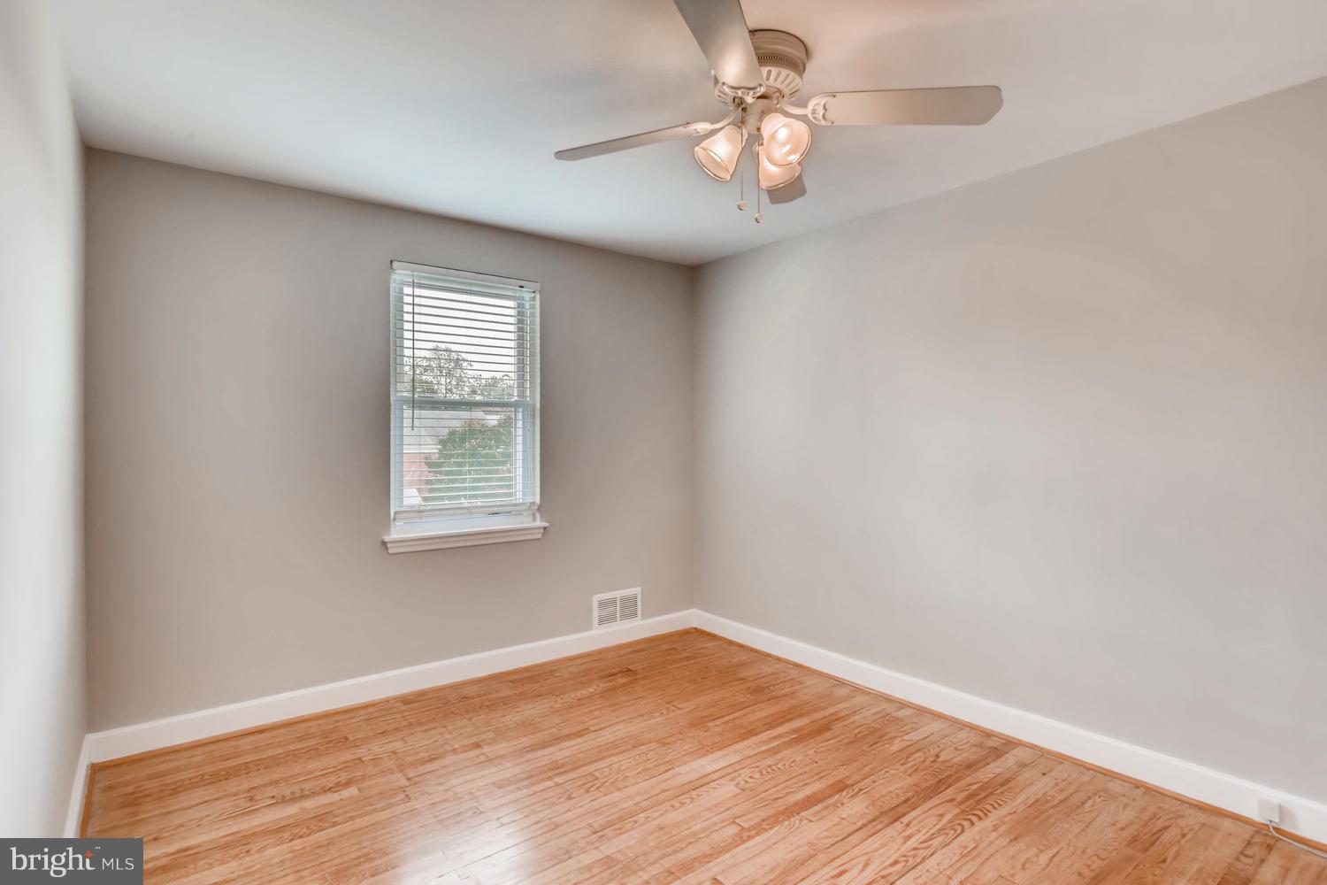 8546 Water Oak Road Baltimore, MD 21234 - Photo 11 of 28 an empty room with wooden floor chandelier fan and window